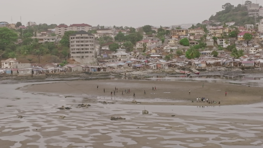 Slow motion aerial footage rotating around a patch land in the bay outside of Freetown, Sierra Leone with buildings in the background.