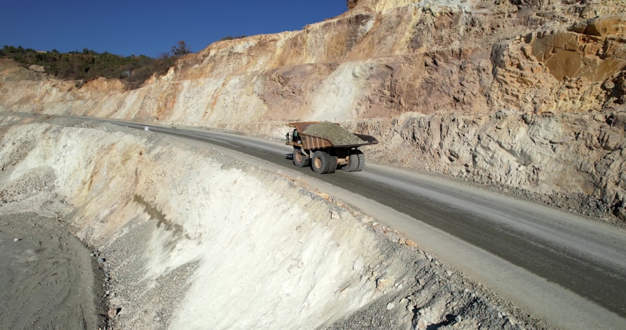 Large quarry dump truck transporting ore on open pit mine, aerial slow motion shot