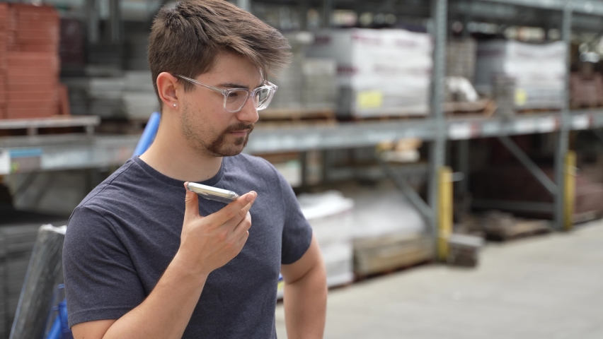 Young man contractor at hardware store talking on phone checking materials.