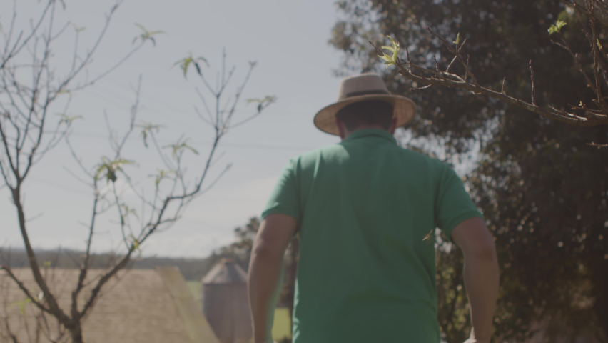 Farmer working, walking with wheelbarrow across farm