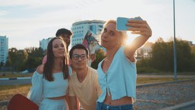 Young multi-ethnic hipster friends on summer holidays make selfie using smartphone at beach. Four young multiracial people spending time together. Friendship, communication, a youth lifestyle concept.