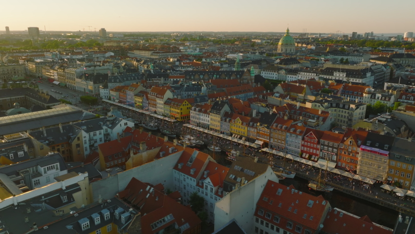 Bright colour townhouses along Nyhavn. Tourist attraction with promenade and old sailboats. Aerial panoramic view at sunset. Copenhagen, Denmark