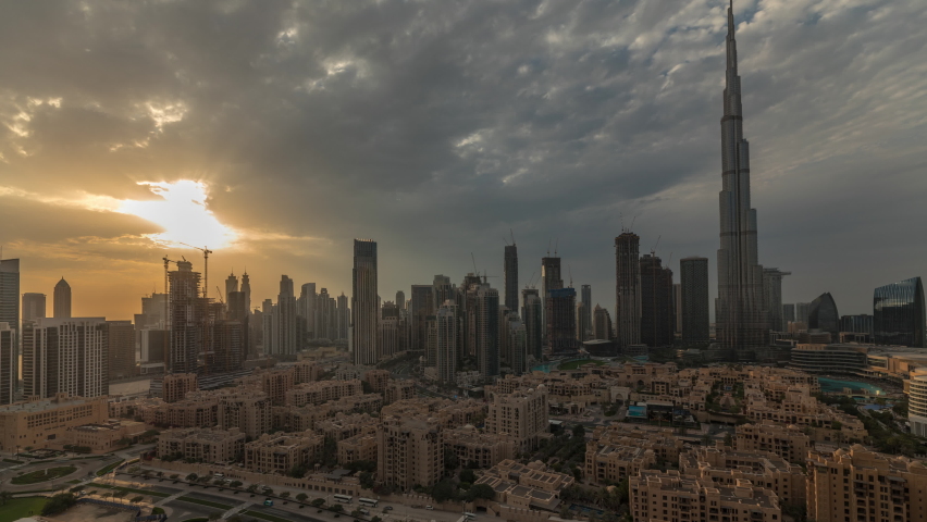 Sunset over Dubai Downtown timelapse with tallest skyscraper and other towers view from the top in Dubai, United Arab Emirates. Rays of light and cloudy orange sky