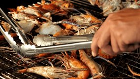 Slow motion video of hand grilling seafood with crab, shrimp and squid-4K, the famous street food of Thailand.