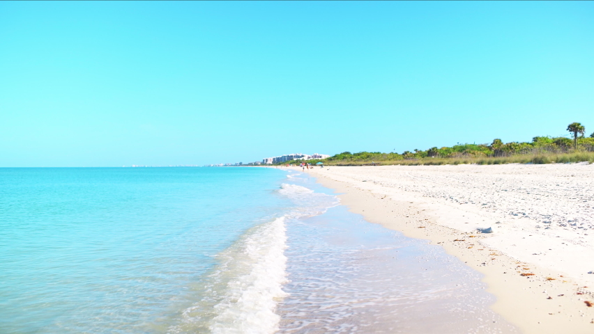 Point of view pov walking on Barefoot Beach, Florida with people in Bonita Springs by turquoise blue green water of Gulf of Mexico and white quartz sand