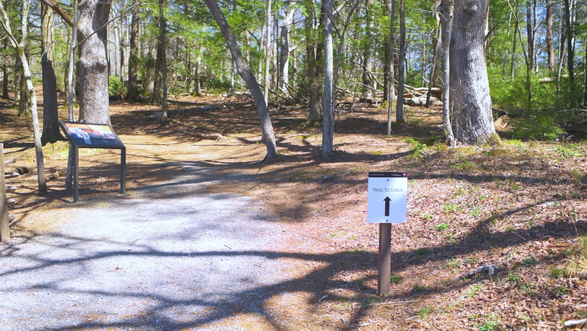 Pov point of view walking on hiking trail with direction sign to log cabin house in forest woods of Great Smoky Mountains National Park of Cades Cove scenic loop in Gatlinburg, Tennessee