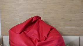 Four years old boy jumping to a red leather bag chair and laughing. 4k real time video footage