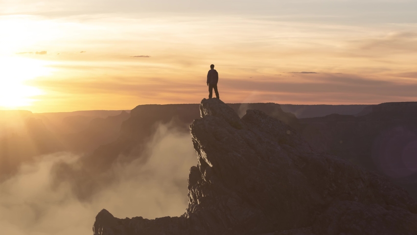 Epic Adventure Composite of Man Hiker on top of a rocky mountain. Dramatic Sunset Sky. 3d Rendering peak. Background landscape from North America. Freedom Concept. Animation