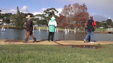 AUCKLAND - JULY 10 2015:People racing remote controlled sailing wooden yachts in a pond.The racing is governed by the same Racing Rules of Sailing that are used for full-sized crewed sailing boats