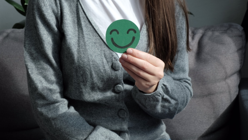 Close-up of female hands holding green happy smile face paper cut sit on couch. Good feedback rating, think positive, customer review, assessment, wellness, world mental health day, Compliment Day | Shutterstock HD Video #1094407433