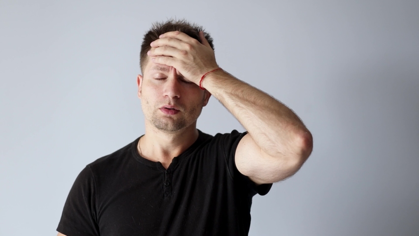 Handsome man in black t-shirt touching his hot forehead with his hand taking temperature | Shutterstock HD Video #1094415879
