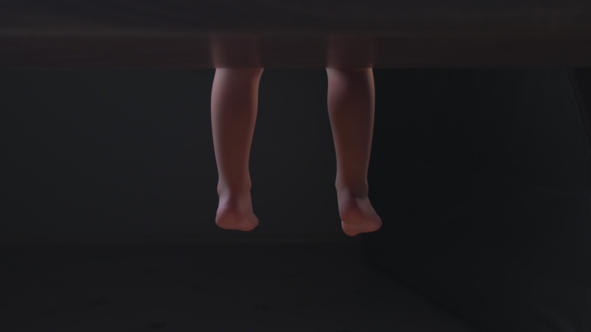 Little boy swinging his legs while sitting ontable