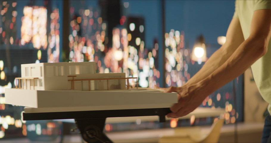 Portrait of Caucasian male architect or student working on a house project scale model late at home, preparing for presentation with a client
