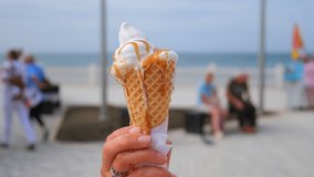 the girl holds in her hand a cone with melted ice cream with topping and it flows down her hand. ice cream flows down your hand. Close-up. Macro. Slow motion. Yellow, pink ice cream - Powered by Shutterstock - Get 15% off with code: PIKWIZARD15