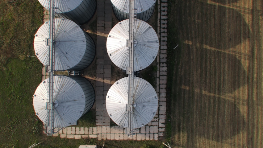 Aerial wide slide shot of agricultural grain silo storage tanks. Top down view Royalty-Free Stock Footage #1094429473