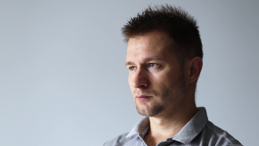 Handsome man in gray t-shirt yawns and covers his mouth with his hand