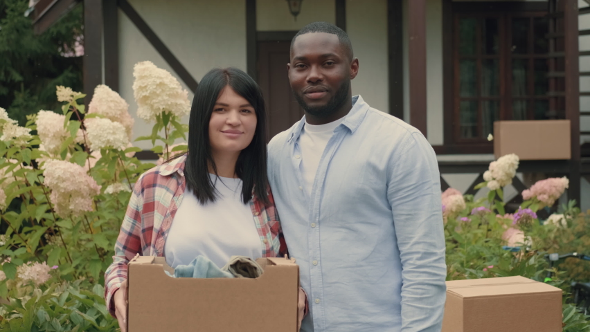Portrait of an African husband and Caucasian wife with boxes in their hands while moving to a new home.Multiracial Family,Mixed Race,Diverse People,Multiethnic Relations