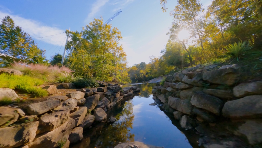 FPV drone shot over reflecting water in Falls park, sunny, fall day in Greenville, USA
