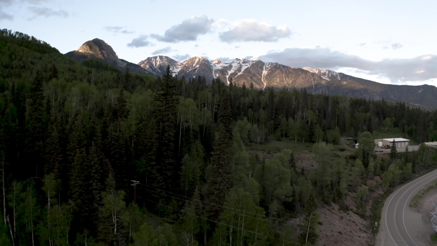 Colorado Rocky Mountains with forest clearing and logging mill, Aerial flyover shot