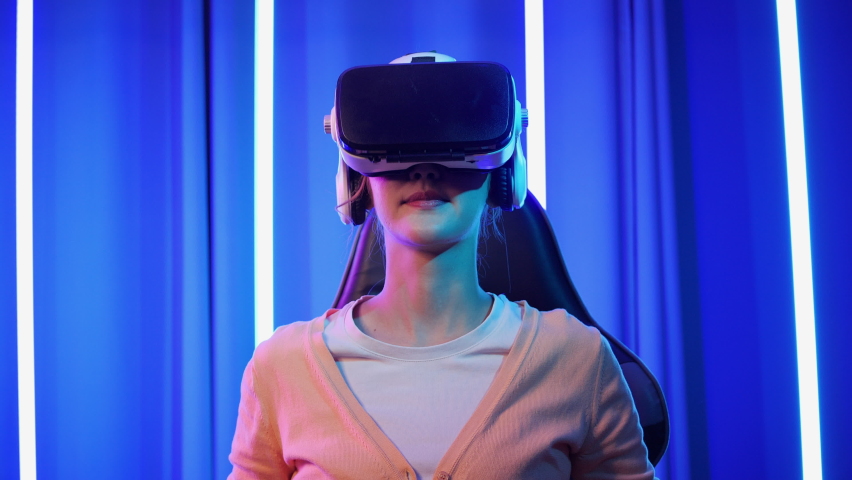 Asian young woman wearing VR headset and playing game online on metaverse. Teenage girls leisure game in neon light room at home. interconnected digital technology. Royalty-Free Stock Footage #1094441725