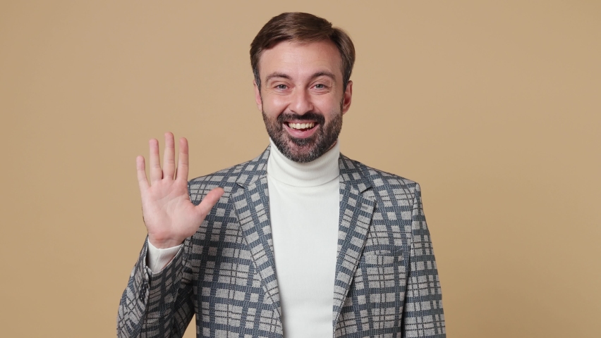 Young employee business man corporate lawyer wear grey suit jacket look around for friend waving meet greet with hand as notices someone work in office isolated on plain pastel light beige background | Shutterstock HD Video #1094455329