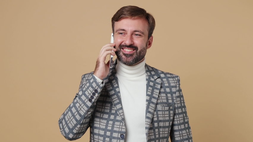 Young happy employee business man corporate lawyer wear grey suit jacket hold use talk on mobile cell phone conduct pleasant conversation work in office isolated on plain pastel light beige background | Shutterstock HD Video #1094455333