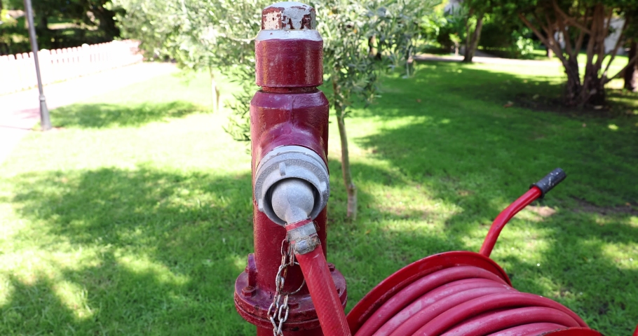 Red fire hydrant with a hose reel in a green park
