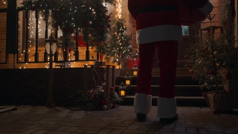Close-up of Santa Claus' feet climbing the stairs and entering the house with a christmas eve gift Arkivvideo