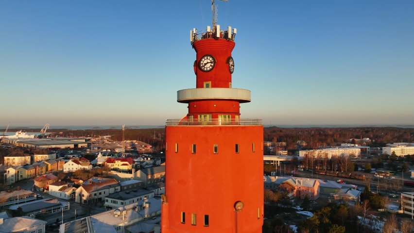 Aerial view closely around the water tower, revealing the cityscape of Hanko, sunset in Uusimaa, Finland - rotating, drone shot