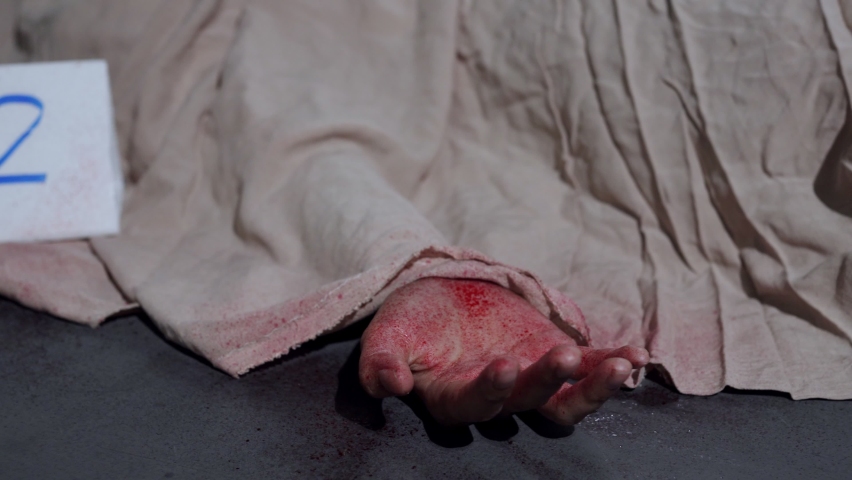 Victim of violent crime scene with cover sheet and evidence marker. Criminal and murder concept