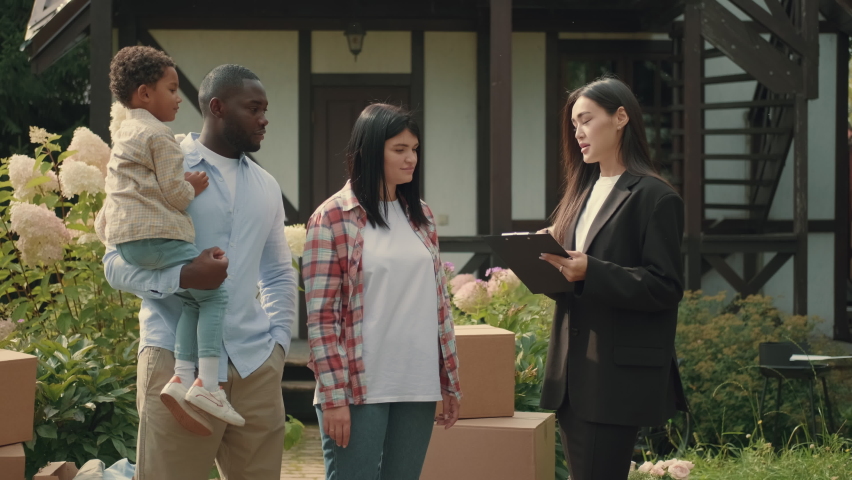 Asian female real estate agent selling a house to a multi-ethnic family. African dad, Caucasian mom, african child.Multiracial Family,Mixed Race,Diverse People,Multiethnic Relations Royalty-Free Stock Footage #1094472633
