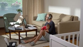 Middle-aged father with baby working from home. A freelance single father with newborn making a video call and working with documents at home. Remote job, multi-tasking, paternity leave. Sequence - Powered by Shutterstock - Get 15% off with code: PIKWIZARD15