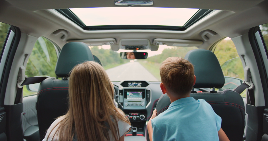 Rear view. Children boy and girl sitting in back seat of car during family trip. Happy family is driving a modern car Royalty-Free Stock Footage #1094482575