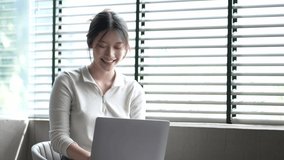 Attractive and happy young female Asian student studying online, sitting at desk, using laptop computer, having video chat, waving, education concept.