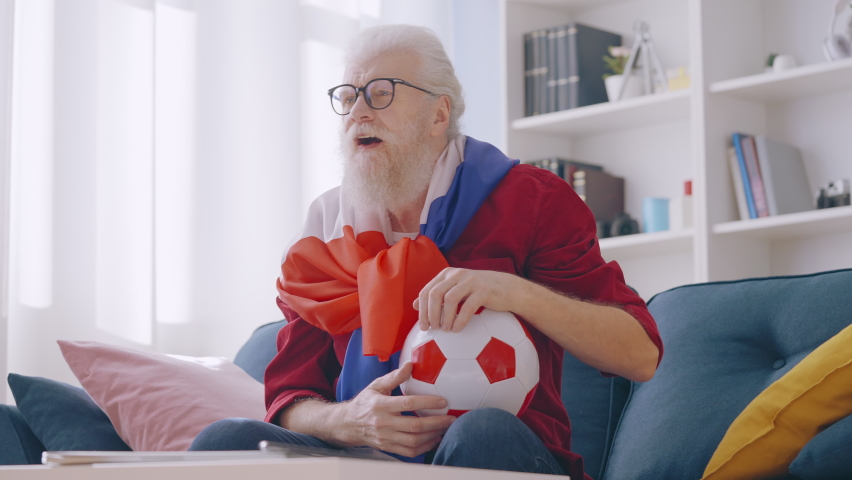 Positive man in his 60s covered with French flag cheering for sports team, hobby
