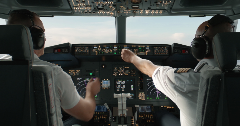 Commercial aircraft pilots adjusting flight parameters of the plane during the flight at high altitude. View from inside the cabin. Real aircraft, daytime shot