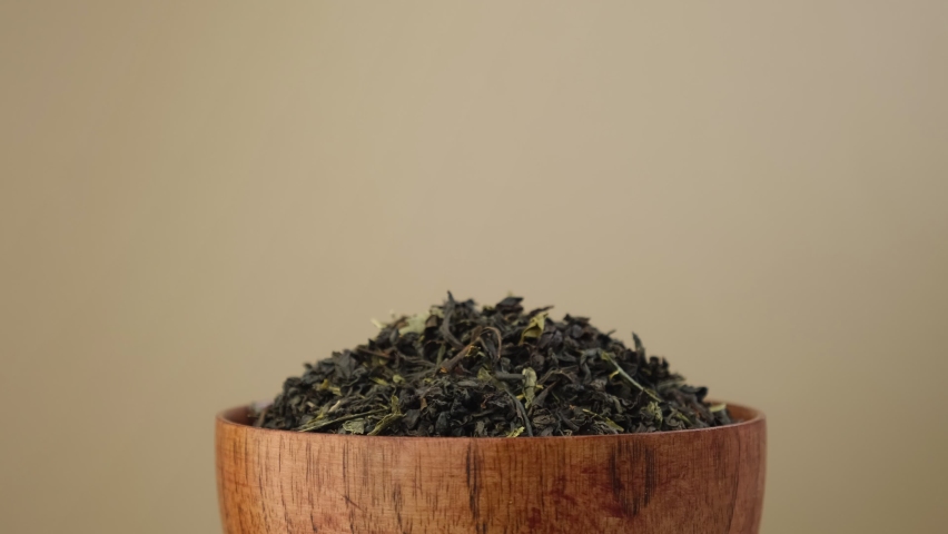 Black Dry Tea Pouring in a Bowl. Pile of Mix Black and Green Tea Leaves. Close Up, Macro. Front View. Texture. Copy Space. Dried Tea is Spinning, Rotating on Turntable. Food and Drink Background Royalty-Free Stock Footage #1094494537
