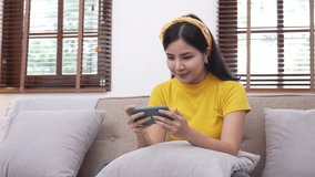 Beautiful Asian girls are excited to play games on the sofa at home.