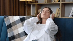 Relaxing time with music. Beautiful young woman sitting in the house choose music and take a rest and listening song with wireless headphone. Lifestyle in living room at house in the morning
