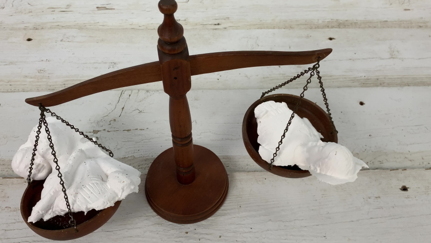 Broken family statuette on the scales of justice in a divorce custody battle | Shutterstock HD Video #1094496365