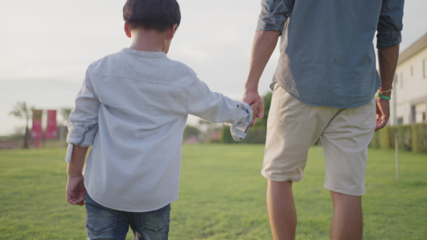 Asian Father and son playing outdoor in grass summer sunny day under sunlight