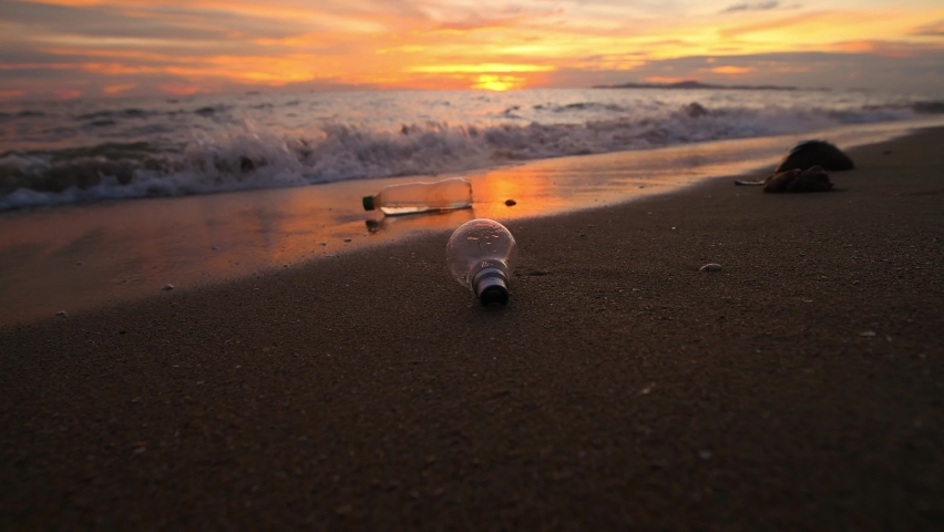 Plastic bottles garbage on sand beach is environment pollution of global with sunset sky background. Royalty-Free Stock Footage #1094506329