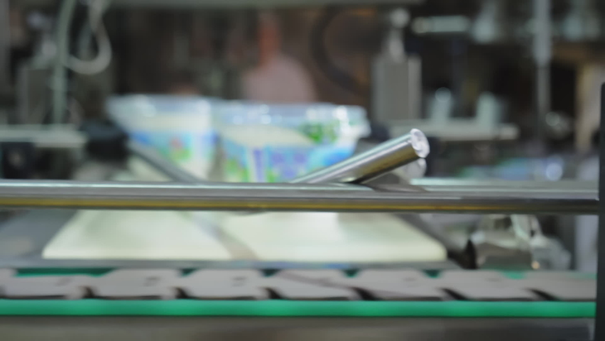 Automated production line. The finished and packaged dairy product moves along the conveyor line. Milk cream in a box. Cottage cheese. Liquid smooth butter in plastic packaging. Close up