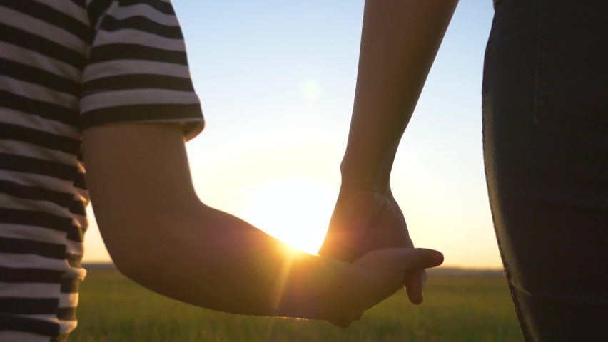 Happy, friendly family. Mother holds the hands of a little son. Hands of parent and child large in the light of a beautiful sunset. Teamwork. Way to success. Royalty-Free Stock Footage #1094515409