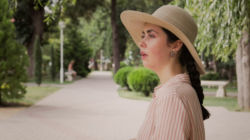 Sunstroke and heatstroke. A sweaty woman in a straw hat is standing on the street, fanning herself with her hand from the heat. Summer vacation and hot temperature. Royalty-Free Stock Footage #1094517191