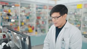 Male pharmacist talkin with customer on computer online counseling and discusses choice of medication in drugstore.