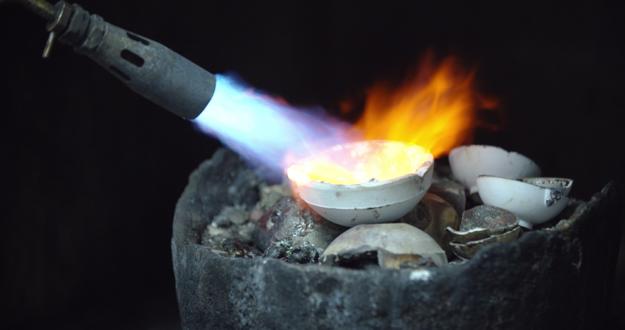 Goldsmith using a heated blow torch to melt precious metals like gold and silver. Jeweler expertly working with elements to hand make jewellery. Royalty-Free Stock Footage #1094529915