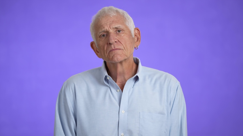 Sad upset worried disturb displeased shocked elderly gray-haired man 70s wears blue shirt sigh surprise put hands on face isolated on solid purple background studio portrait | Shutterstock HD Video #1094531371