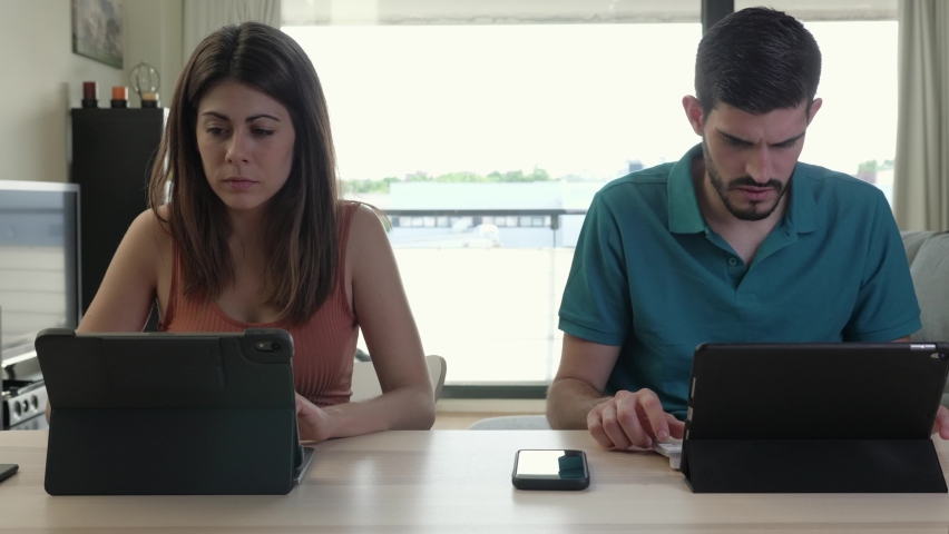 portrait of young couple working at home with their tablets