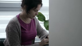 Young Woman Writing Checklist Note. Housewife Sitting at Desk Table Near Window in Apartment. 2x Slow motion 60fps 4K